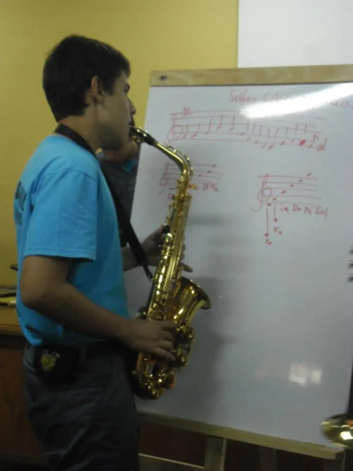 Joven saxofonista practicando frente a una pizarra con notación musical